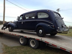 The 1939 LaSalle ambulance is slowly rolled off the trailer